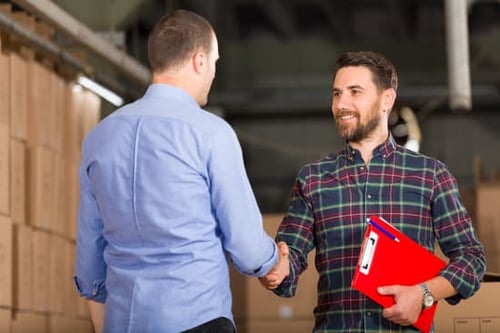 two men shaking hands in a warehouse